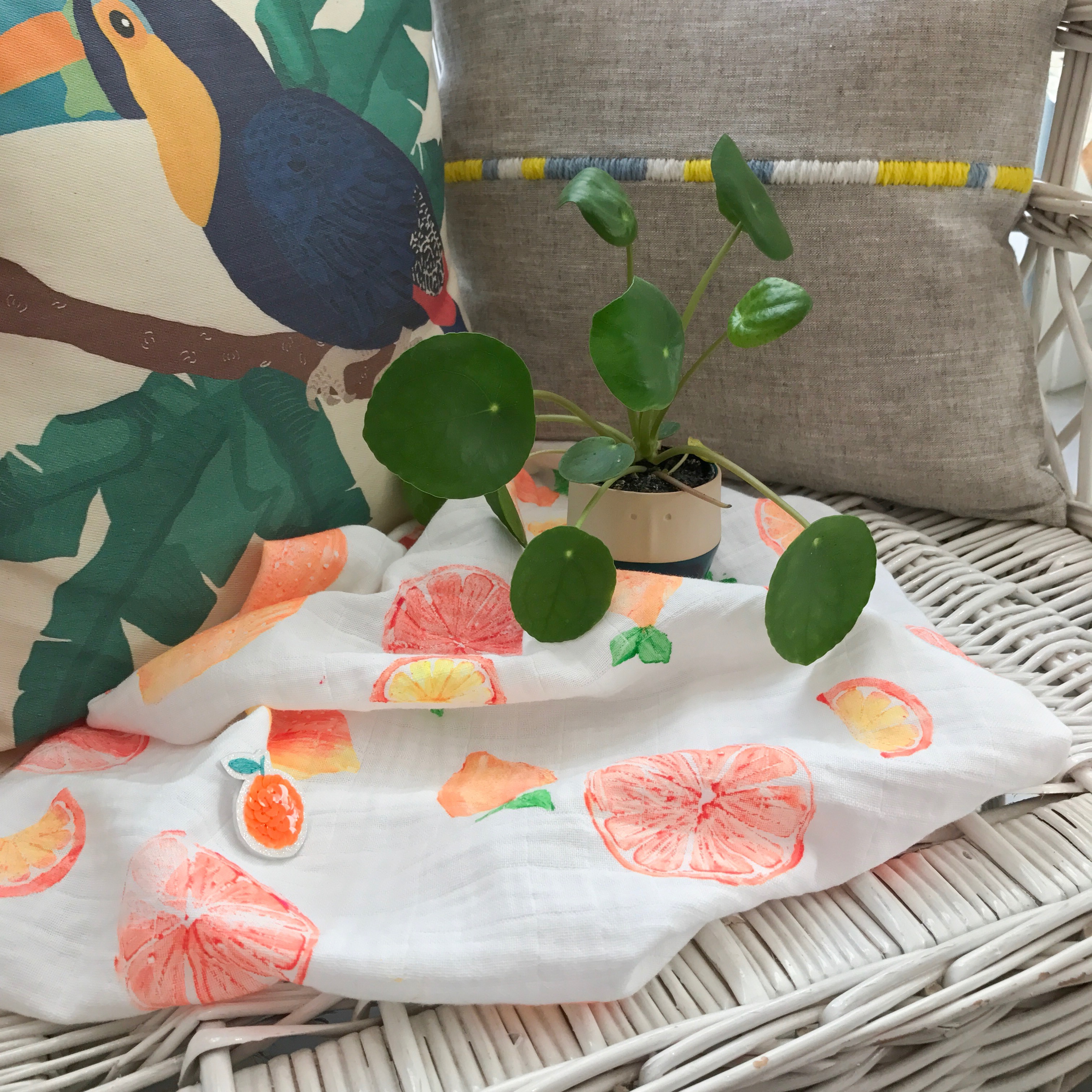 lange pour bébé avec des oranges, une broche Parisi et un pilea