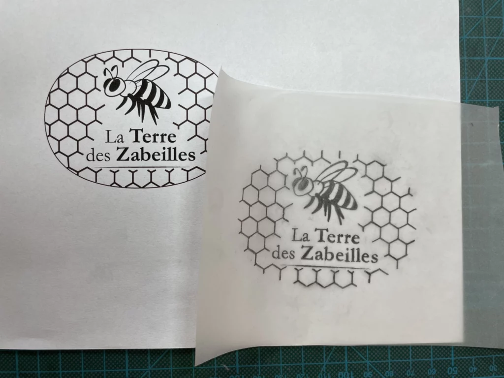 Logo d'abeille noire tampon artisanal Kraftille en gomme japonaise Hinodewashi, motif créatif, sur papier parchemin quadrillé.